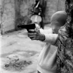 © Letizia Battaglia, Palermo, 1982, vicino alla chiesa di Santa Chiara un bambino gioca a fare il killer con una calzamaglia in testa (il bambino è il figlio della giornalista di destra Marianna Bartocelli)