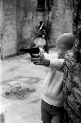 © Letizia Battaglia, Palermo, 1982, vicino alla chiesa di Santa Chiara un bambino gioca a fare il killer con una calzamaglia in testa (il bambino è il figlio della giornalista di destra Marianna Bartocelli)