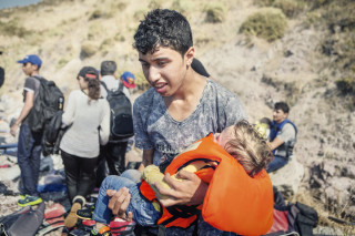 2015. Lesvos. Greece. A young Syrian carrying his little brother in his arms after disembarking with around 55 other people on the Greek island of Lesvos.